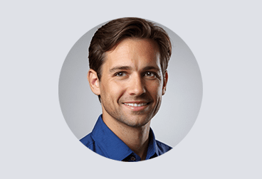 face of smiling male freelancer with dark hair wearing a blue shirt