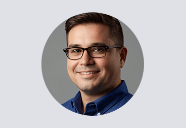 face of male freelancer with dark hair wearing glasses and a dark blue shirt