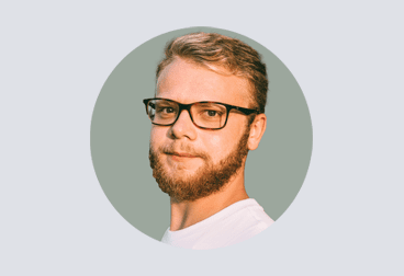 Head and shoulders photo of male freelancer with blonde hair wearing glasses and a white shirt